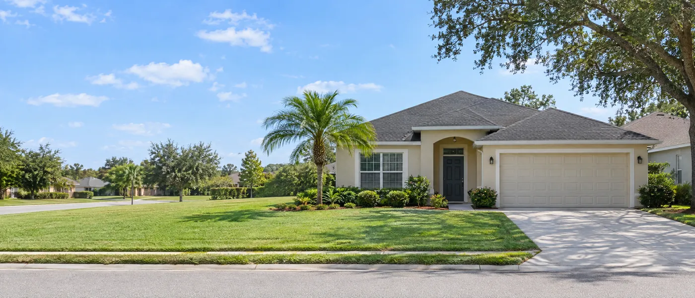 Single-story Central Florida home with a shingle roof, palm tree and wide lawn