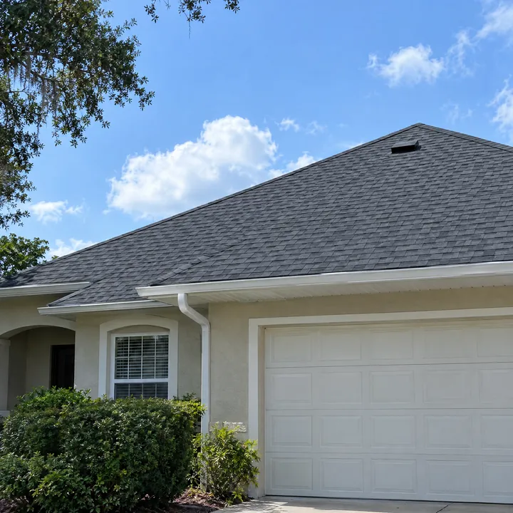 Florida home with a dark gray shingle roof and a white garage door